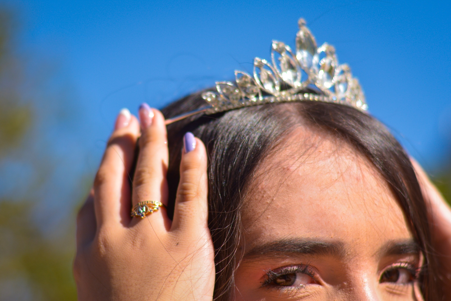 Manos ajustando la corona bajo el cielo azul