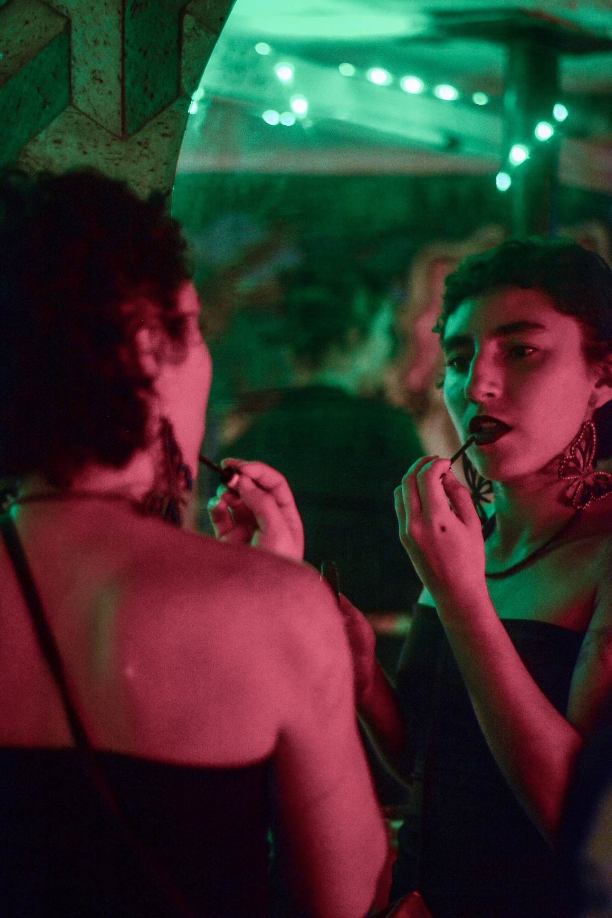 Reflejo en espejo: maquillándose los labios bajo luz verde