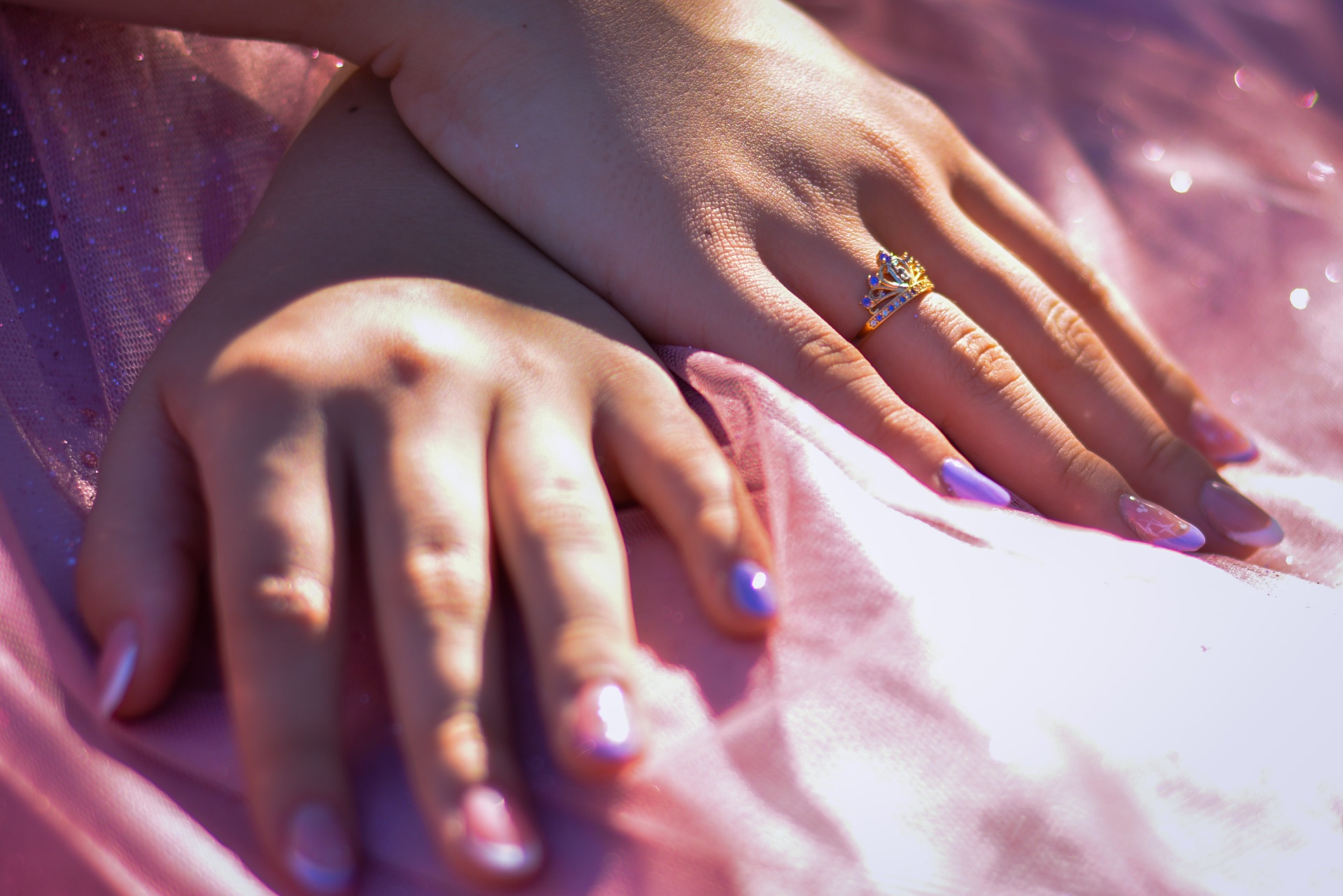 Manos cruzadas con anillo de corona sobre el vestido rosa