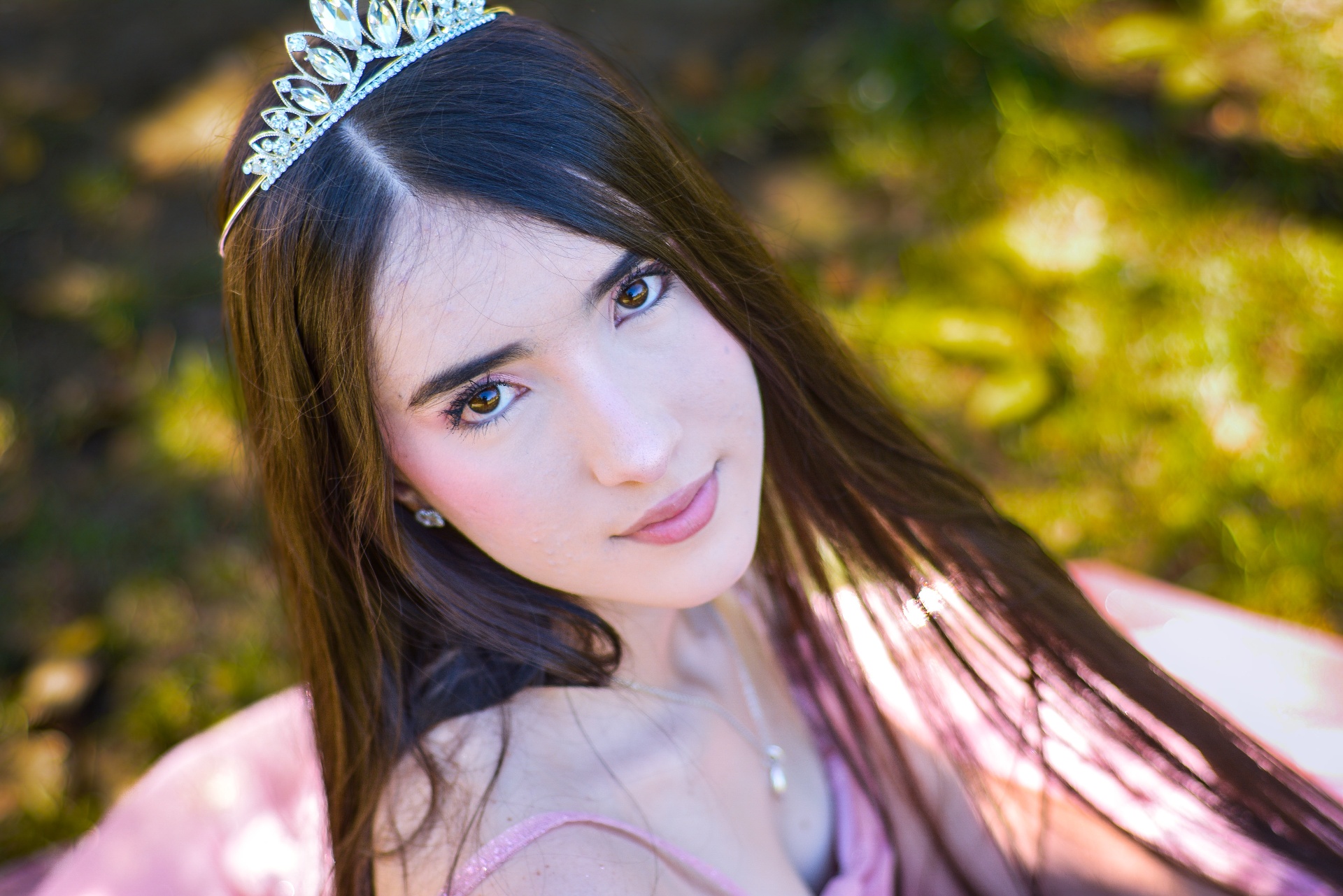 Retrato cercano con corona y vestido rosa sobre el césped