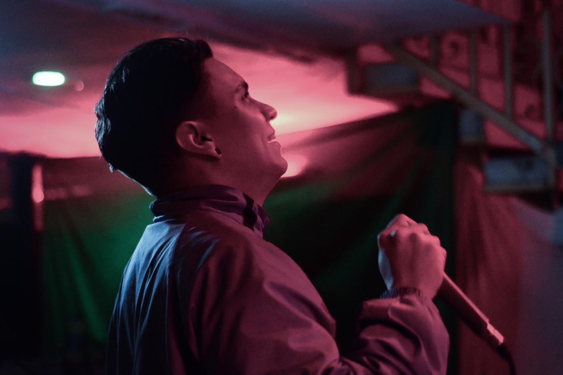 Perfil de cantante mirando arriba bajo luz magenta