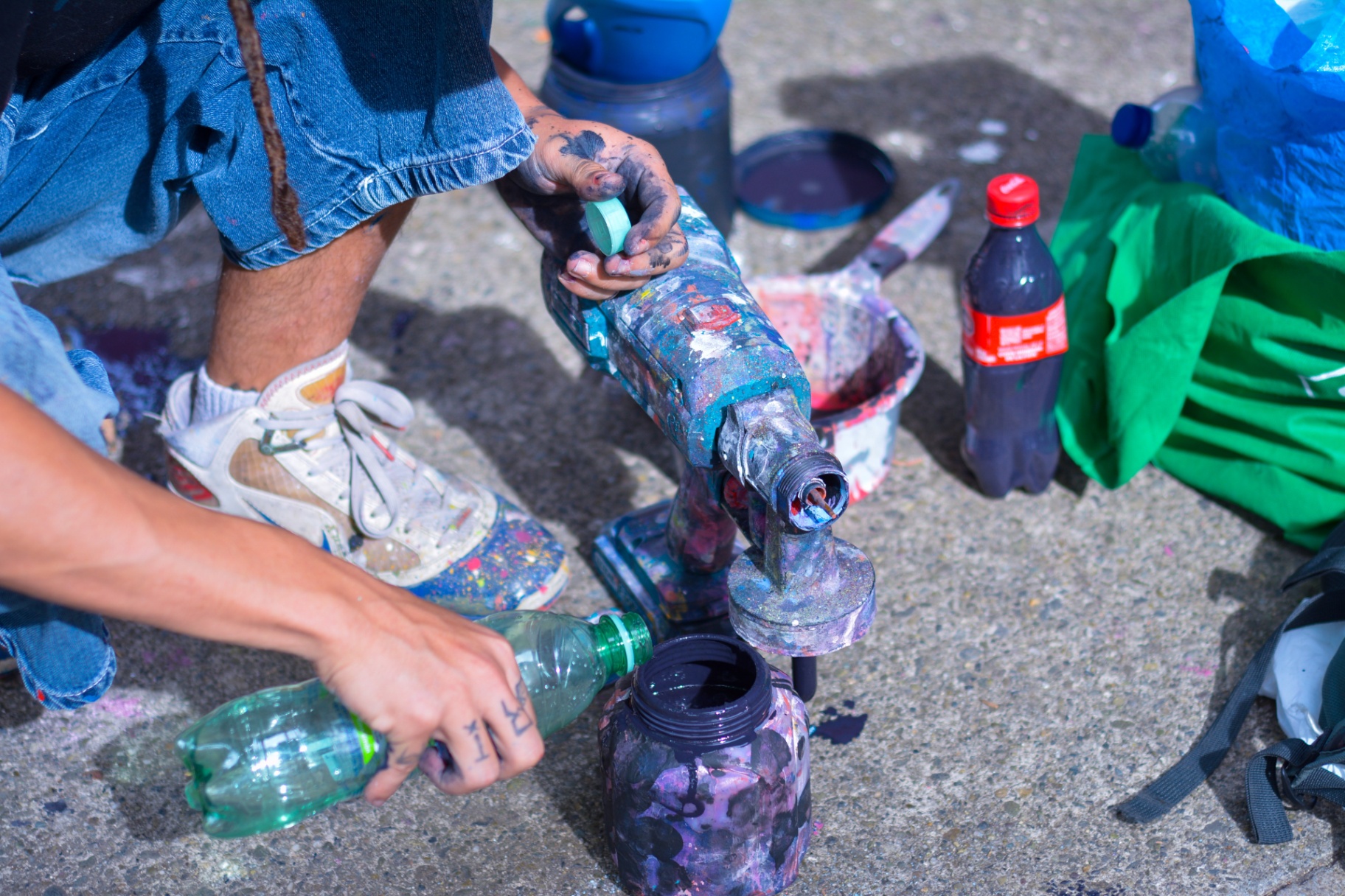 Manos tatuadas vertiendo pintura desde una botella