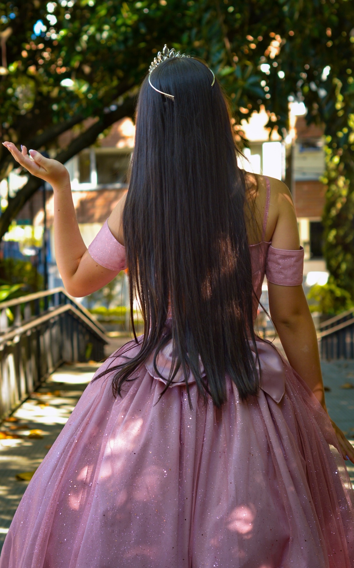 Espalda de la quinceañera con cabello largo y vestido rosa brillante