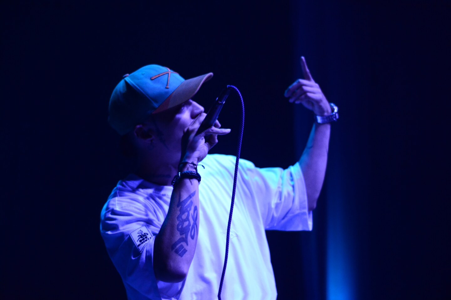 MC señalando al cielo mientras canta, luz azul