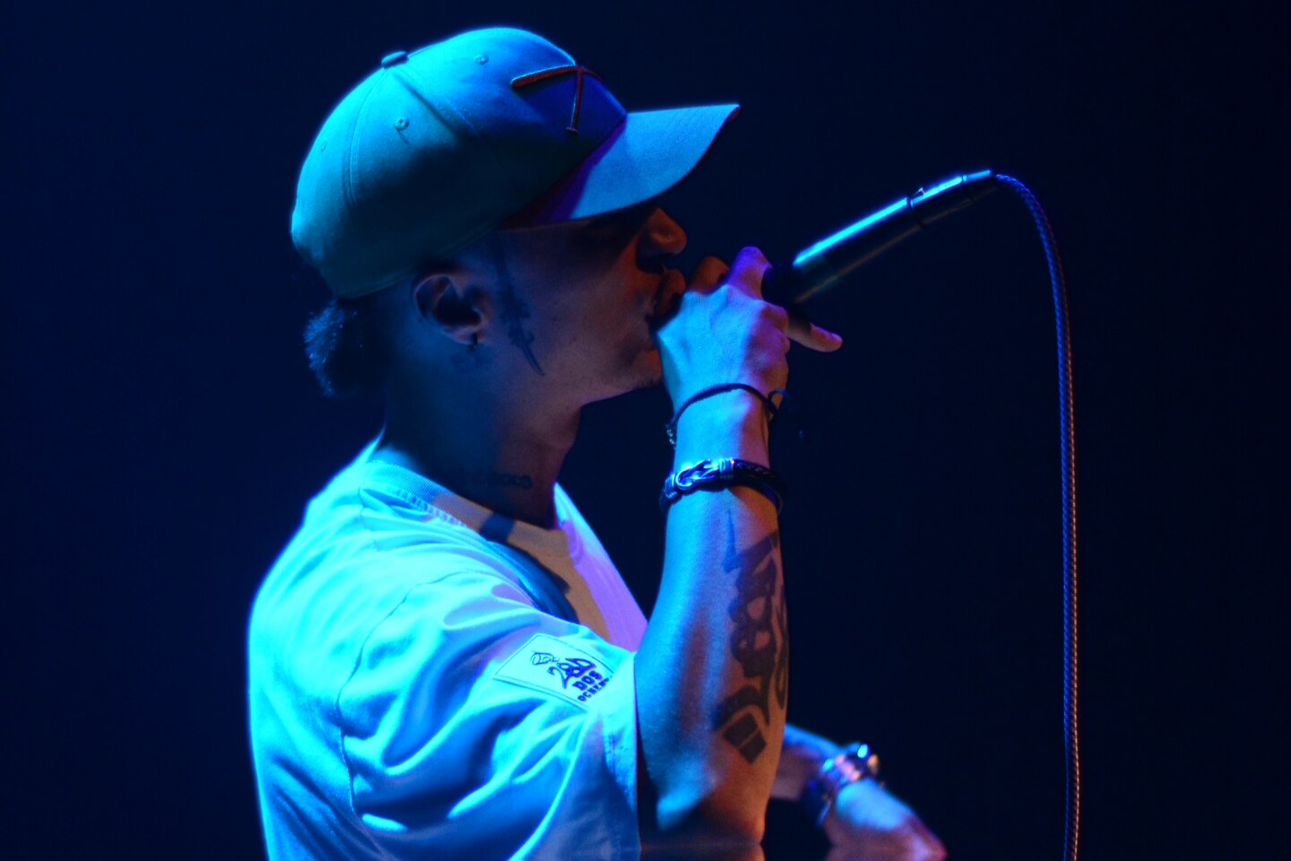 Perfil cercano del MC al micrófono, azul cobalto