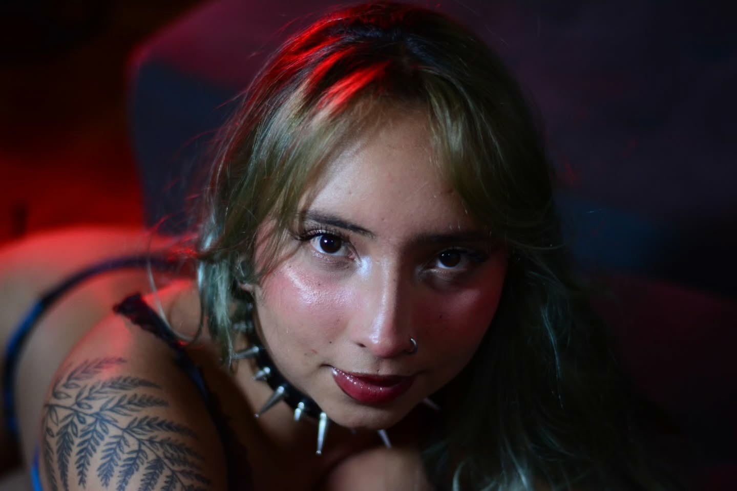 Retrato íntimo con luz roja y collar de spikes